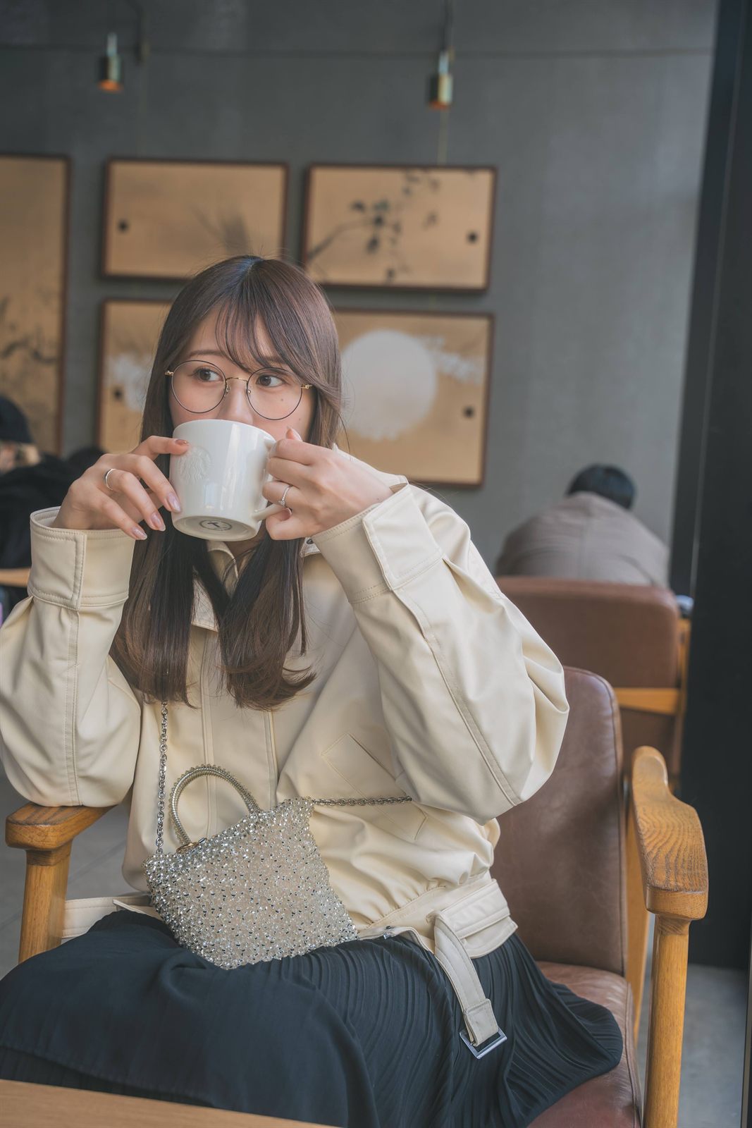 カフェでマグカップを両手に持つ女性